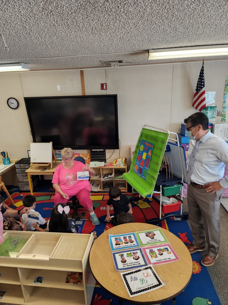 Superintendent visits a school classroom as teacher is teaching students on the carpet some flash cards about their alphabet