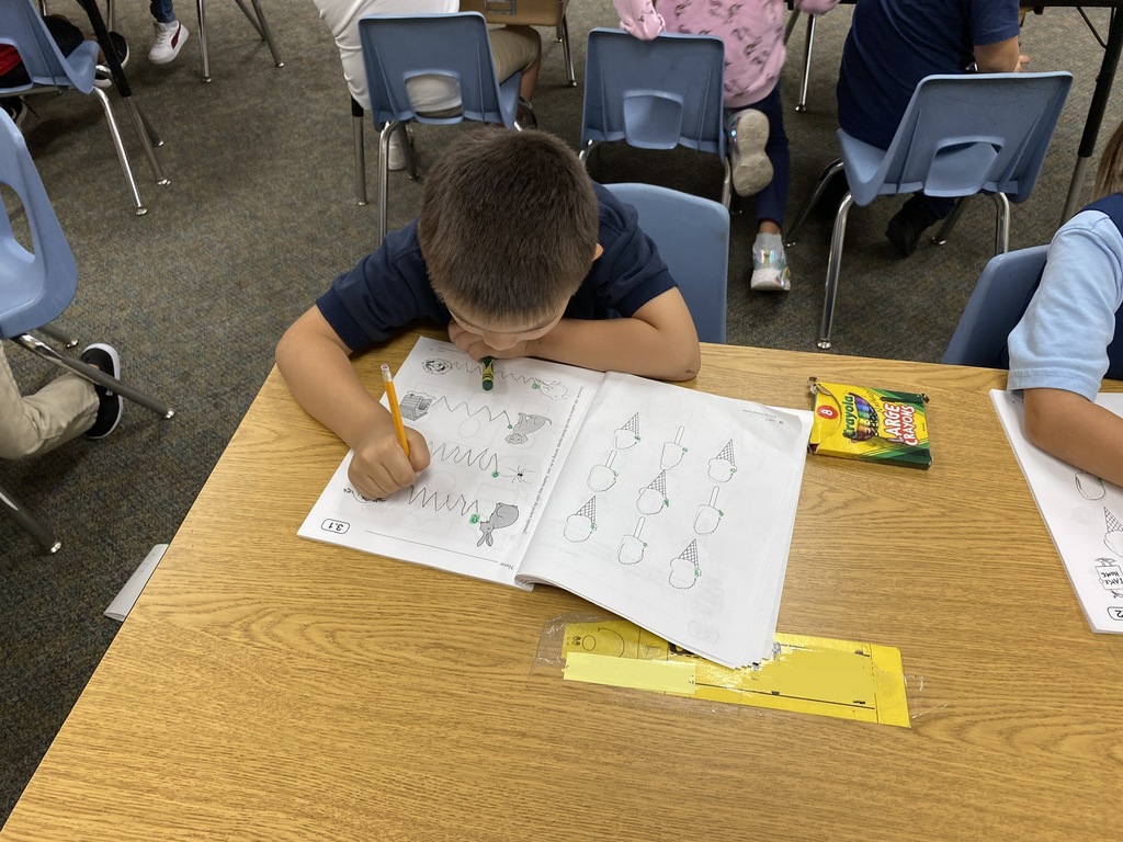 Student working on tracing the line on a kindergarten worksheet.