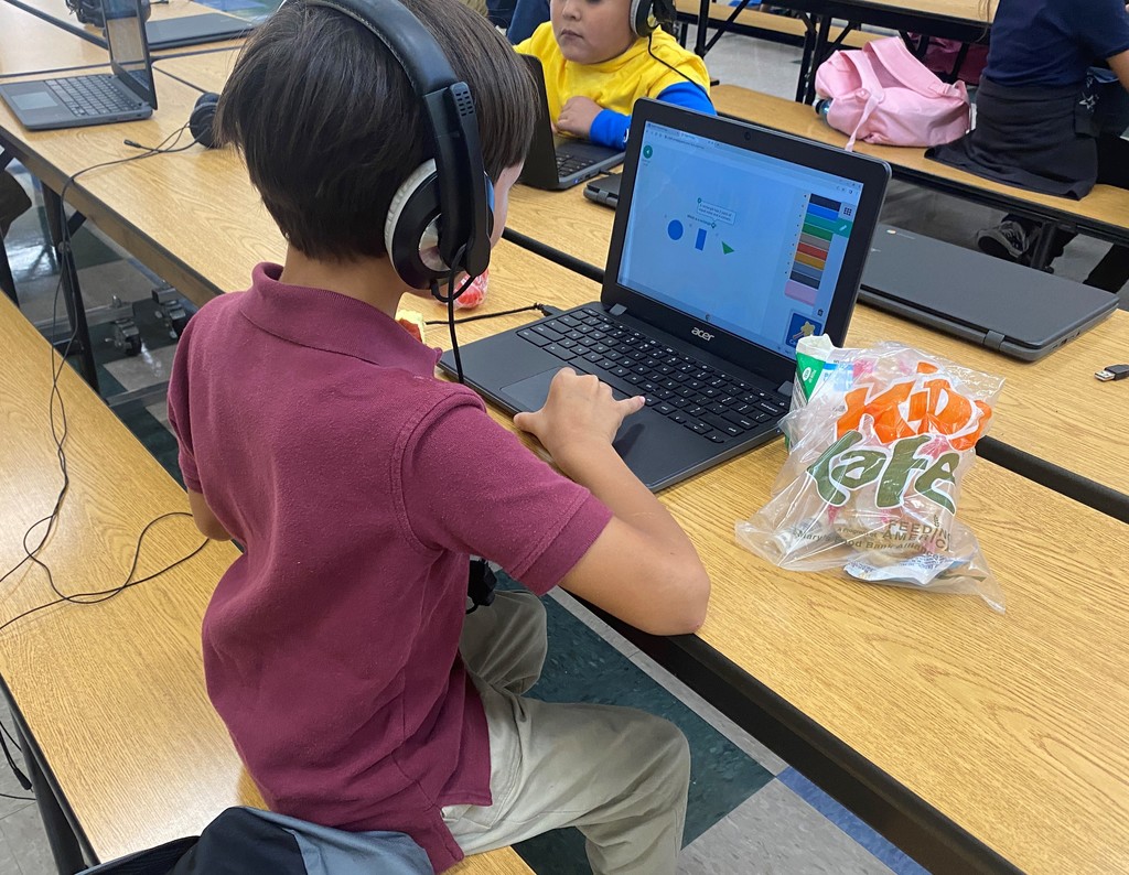 Student using headphones and a laptop working on a math problem.