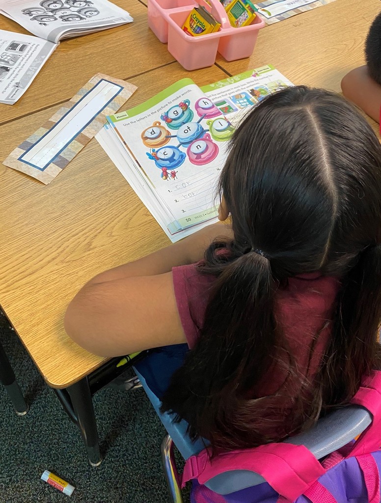 Student at her desk working on a workbook about spelling words.