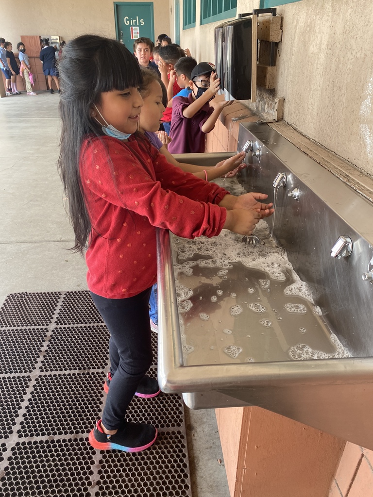 Student washing her hands with soap and water at the sink.