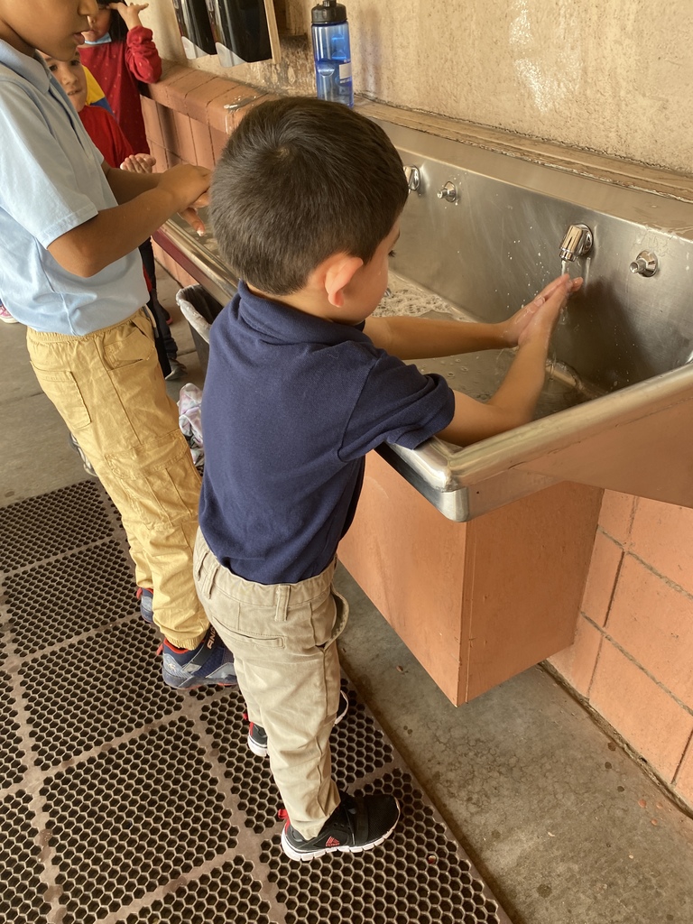 Student washing his hands at the sink with soap and water.
