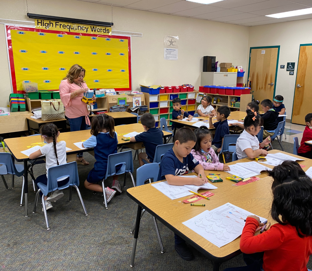 Kindergarten students working on some worksheets with their teacher inside their classroom.
