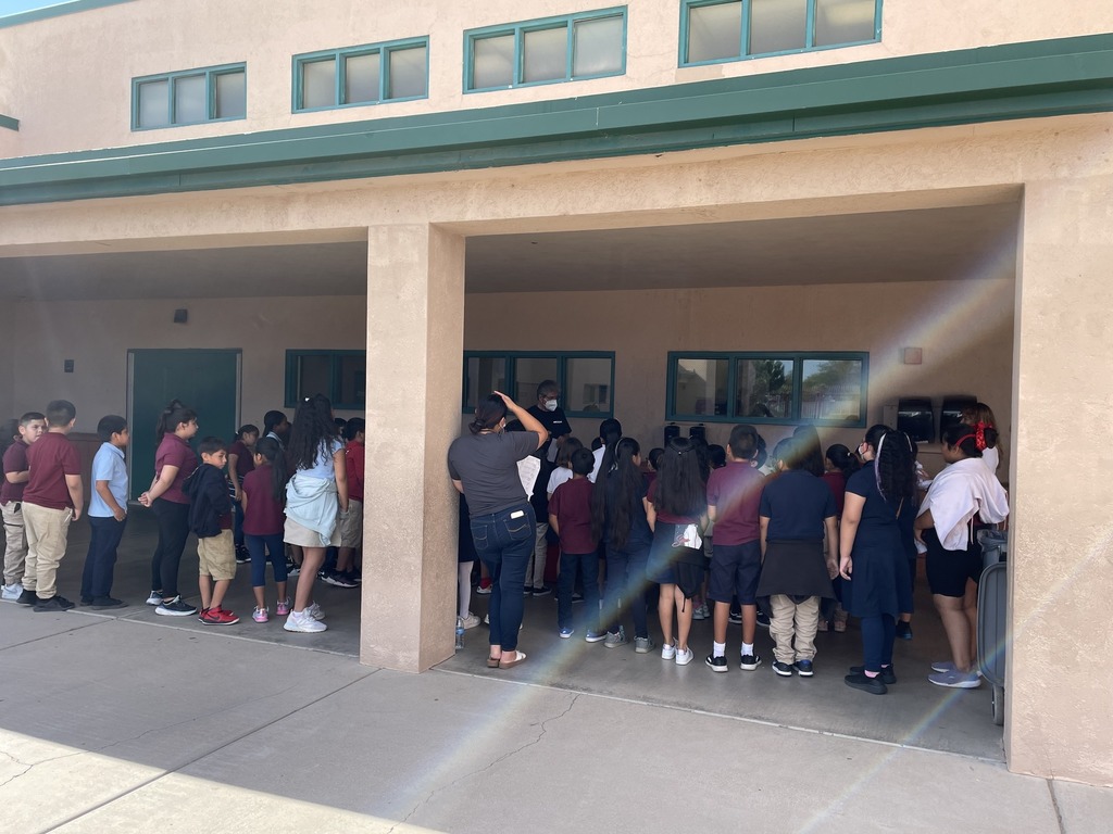 Students in 3rd grade all listening to the teacher in the playground go over the rules of the playground.