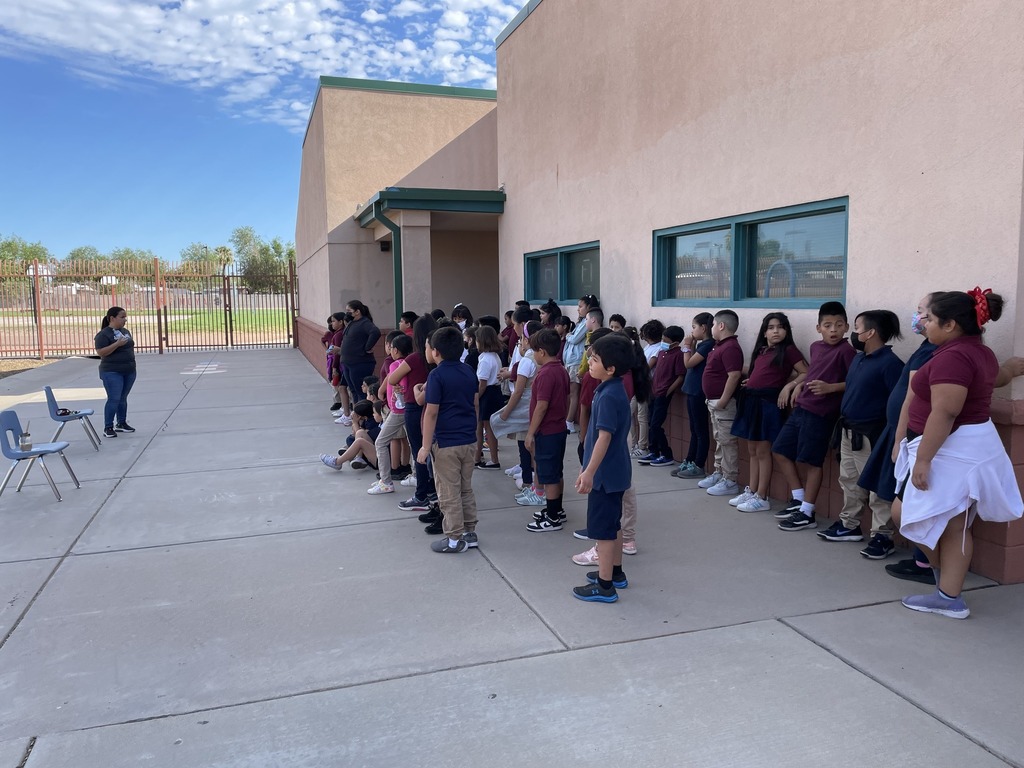 Students in 3rd grade all listening to the teacher in the playground go over the rules of the playground.