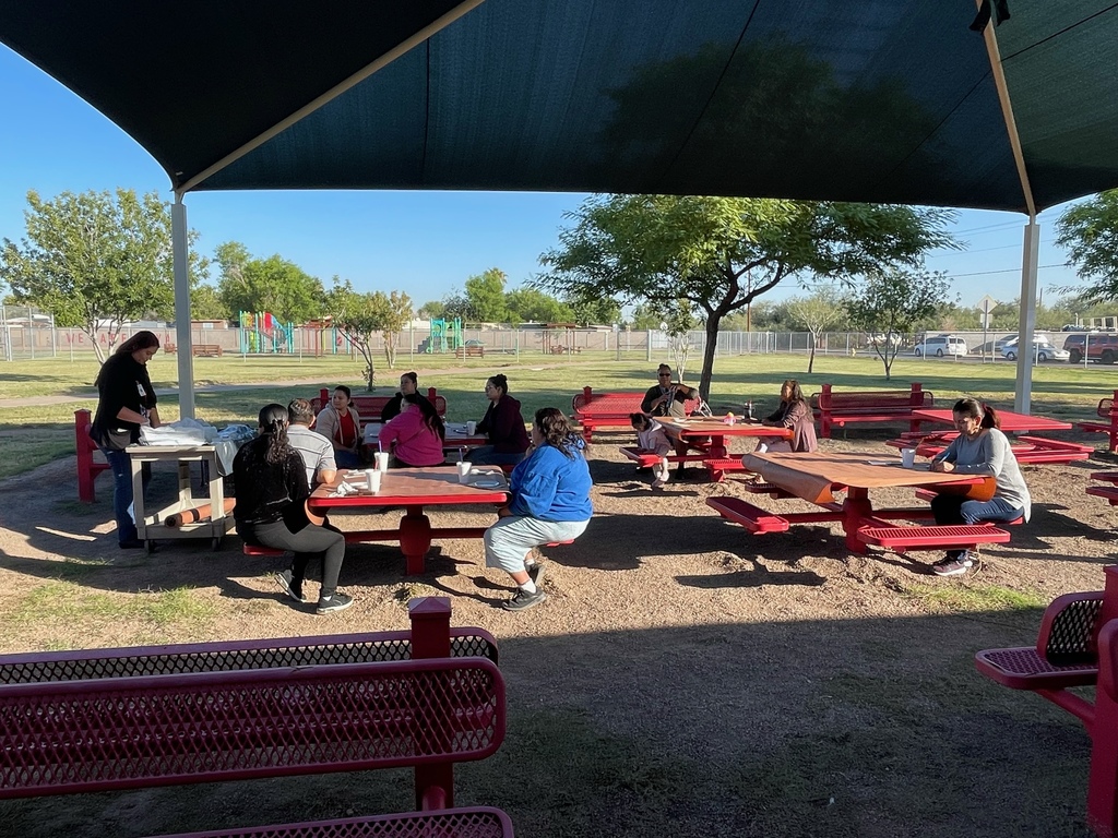 Parents and parent educator outside sitting in the picnic tables learning on how to frost and decorate cupcakes.
