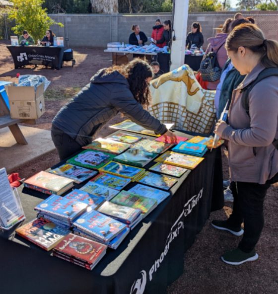 Volunteer showing books to two community members.